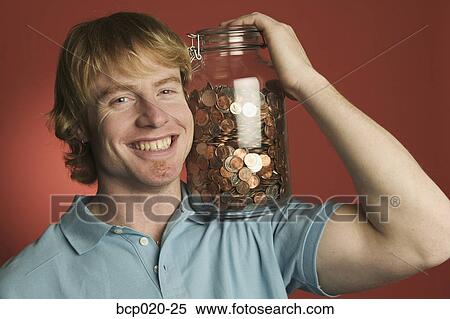 Man smiling while holding a large glass coin jar. View Large Photo Image Stock Photography - Man smiling while holding a large glass coin jar.. Fotosearch
