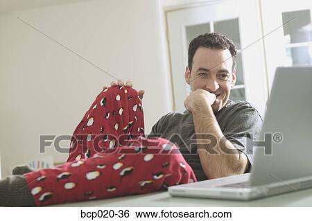 Man working on a laptop while in his pajamas. View Large Photo Image Stock Photograph - Man working on a laptop while in his pajamas.. Fotosearch