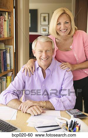 Portrait of a middleaged couple in their home office paying bills. View Large Photo Image Stock Image - Portrait of a middleaged couple in their home office paying bills.. Fotosearch