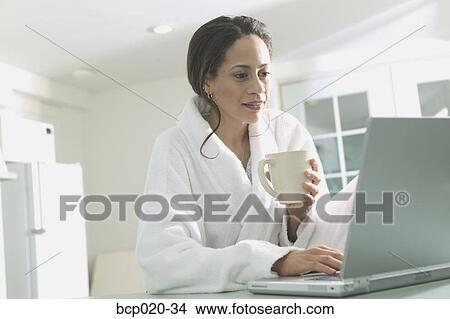 Woman in a bathrobe types at a laptop. View Large Photo Image Picture - Woman in a bathrobe types at a laptop.. Fotosearch