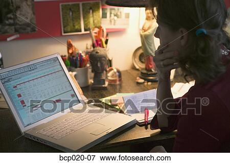 Woman working on her budget at a home office desk. View Large Photo Image Stock Photo - Woman working on her budget at a home office desk.. Fotosearch