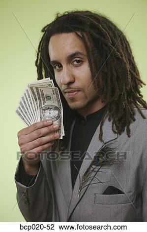 Young man holds a handful of money by his face. View Large Photo Image Stock Image - Young man holds a handful of money by his face.. Fotosearch