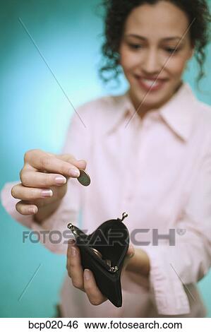 Young woman dropping coins into purse. View Large Photo Image Stock Photograph - Young woman dropping coins into purse.. Fotosearch