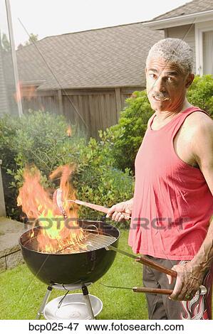 A man grilling in his backyard View Large Photo Image Stock Photo - A man grilling in his backyard. Fotosearch