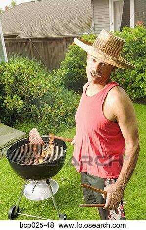 A man grilling in his backyard View Large Photo Image Stock Photo - A man grilling in his backyard. Fotosearch