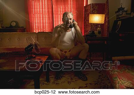 Stock Image - A man in his underwear smoking a cigar. Fotosearch