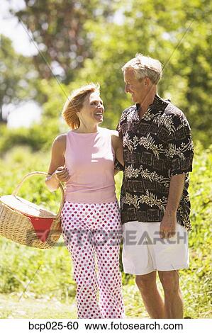 Stock Image - Middle-aged couple on their way to a picnic. Fotosearch