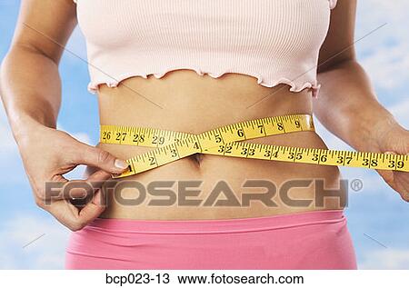 A woman measuring her waist View Large Photo Image Stock Image - A woman measuring her waist. Fotosearch