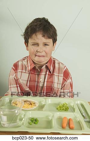 A young boy unhappy with his plate of food View Large Photo Image Stock Image - A young boy unhappy with his plate of food. Fotosearch