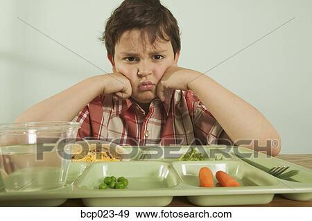 Stock Photo - A young boy unhappy with his plate of food. Fotosearch