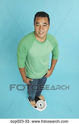 Stock Image - Man standing on a scale. Fotosearch