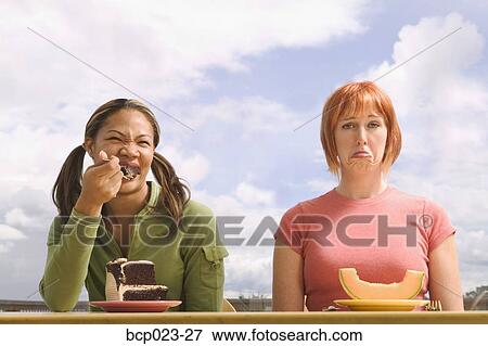 Stock Photo - Two women eating different food. Fotosearch