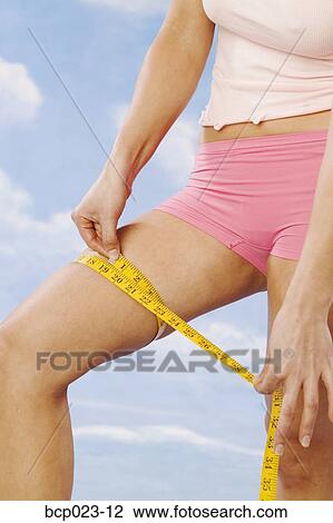 Woman checking her thigh with a tape measure View Large Photo Image Stock Image - Woman checking her thigh with a tape measure. Fotosearch