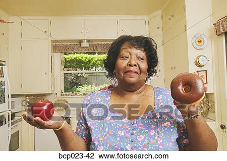Woman deciding whether to eat an apple or doughnut View Large Photo Image Stock Image - Woman deciding whether to eat an apple or doughnut. Fotosearch