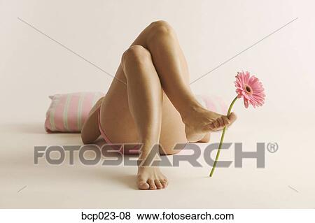 Woman lying down with a flower between her toes View Large Photo Image Stock Photo - Woman lying down with a flower between her toes. Fotosearch