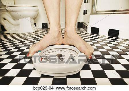 Woman weighing herself on a bathroom scale View Large Photo Image Picture - Woman weighing herself on a bathroom scale. Fotosearch