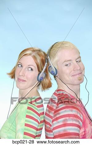 Young couple listening through headsets View Large Photo Image Stock Photo - Young couple listening through headsets. Fotosearch