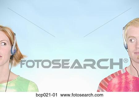 Young man and woman listening to music through headsets View Large Photo Image Stock Image - Young man and woman listening to music through headsets. Fotosearch