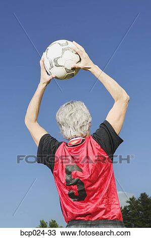 Stock Image - A mature female soccer player throwing the ball in. Fotosearch