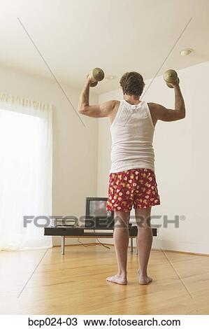 A middle-aged man lifting weights while watching TV View Large Photo Image Stock Image - A middle-aged man lifting weights while watching TV. Fotosearch
