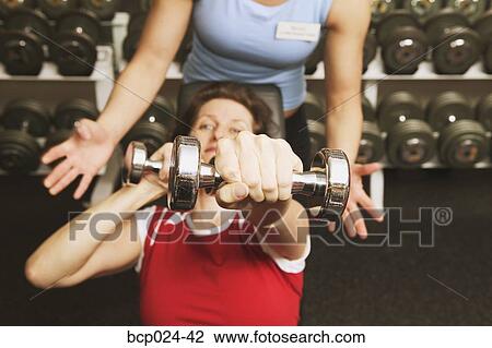 A woman lifting weights with a personal trainer View Large Photo Image Stock Image - A woman lifting weights with a personal trainer. Fotosearch