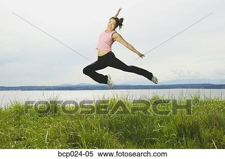Stock Photography - A young woman jumping through the air. Fotosearch