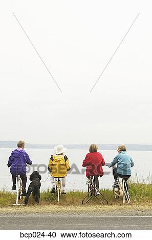 Stock Image - Four women on stationary bikes. Fotosearch