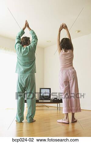 Stock Image - Middle-aged couple exercising to a TV program. Fotosearch