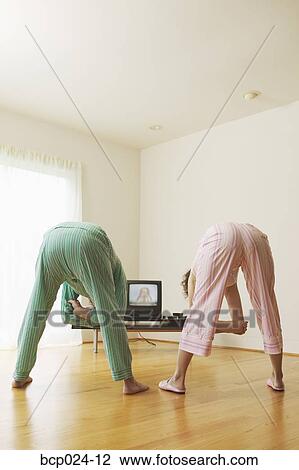 Stock Image - Middle-aged couple exercising to a TV program. Fotosearch