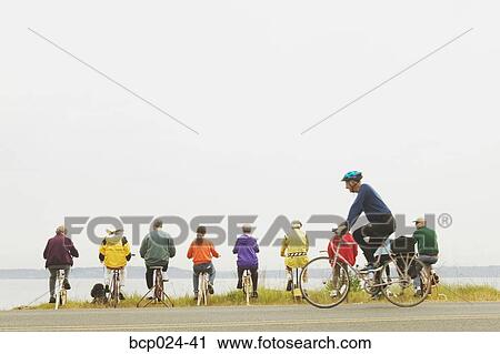 Stock Image - Nine people on exercycles and one on a bike. Fotosearch