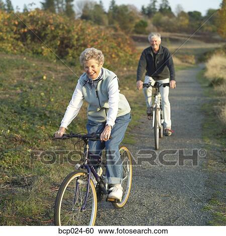 Stock Image - Senior couple riding bikes on a trail. Fotosearch