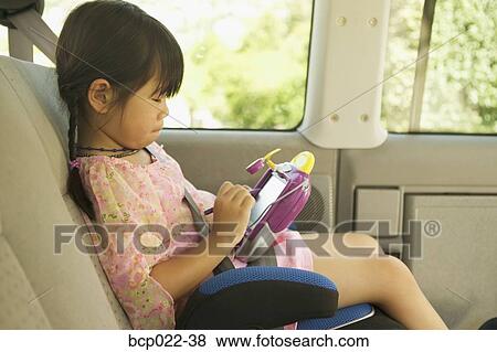 A girl in her car seat playing with an electronic toy View Large Photo Image Stock Photo - A girl in her car seat playing with an electronic toy. Fotosearch