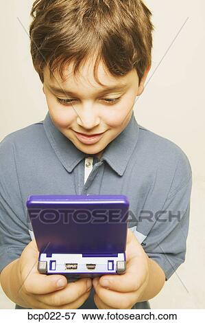 Stock Photo - A little boy playing a computerized game. Fotosearch