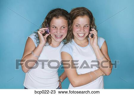Teenaged twins using mobile phones View Large Photo Image Stock Image - Teenaged twins using mobile phones. Fotosearch