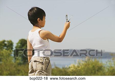 Young boy taking a photo with his mobile phone View Large Photo Image Stock Photo - Young boy taking a photo with his mobile phone. Fotosearch