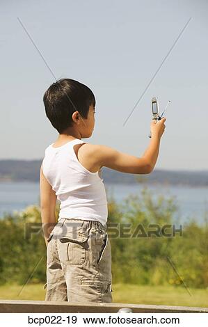 Young boy taking a photo with his mobile phone View Large Photo Image Stock Photo - Young boy taking a photo with his mobile phone. Fotosearch