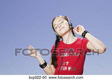 Young girl listening to tunes through a headset View Large Photo Image Stock Image - Young girl listening to tunes through a headset. Fotosearch