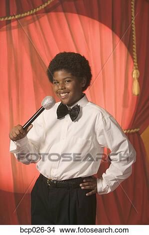 Boy on stage holding a microphone View Large Photo Image Picture - Boy on stage holding a microphone. Fotosearch