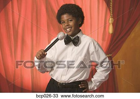 Stock Image - Boy on stage holding a microphone. Fotosearch