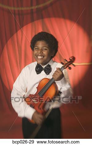 Boy on stage holding a violin View Large Photo Image Stock Photo - Boy on stage holding a violin. Fotosearch