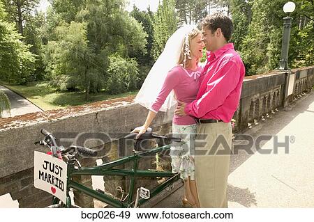 Stock Photo - Newlyweds with a tandem bike. Fotosearch