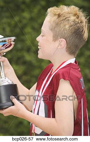Profile of a boy holding a trophy View Large Photo Image Stock Photo - Profile of a boy holding a trophy. Fotosearch
