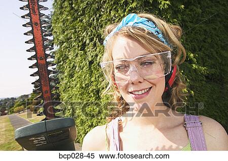 Stock Photography - Portrait of woman with power hedge trimmer. Fotosearch