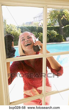 Woman on a cordless phone while cleaning View Large Photo Image Stock Photo - Woman on a cordless phone while cleaning. Fotosearch