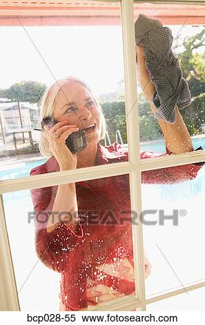 Woman on a cordless phone while cleaning View Large Photo Image Stock Photography - Woman on a cordless phone while cleaning. Fotosearch