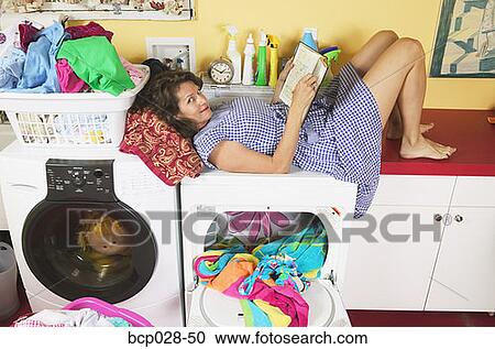 Woman reading while doing laundry View Large Photo Image Stock Image - Woman reading while doing laundry. Fotosearch