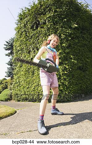 Woman with a power hedge trimmer View Large Photo Image Picture - Woman with a power hedge trimmer. Fotosearch