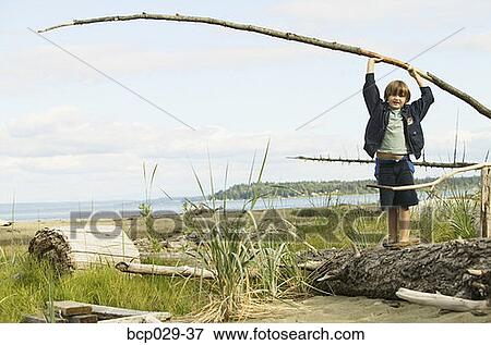 Boy playing on a log at the beach View Large Photo Image Stock Photo - Boy playing on a log at the beach. Fotosearch