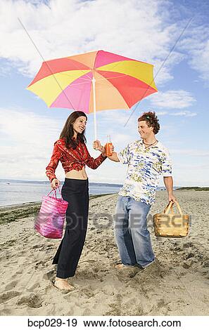 Couple preparing to picnic at the beach View Large Photo Image Stock Photo - Couple preparing to picnic at the beach. Fotosearch