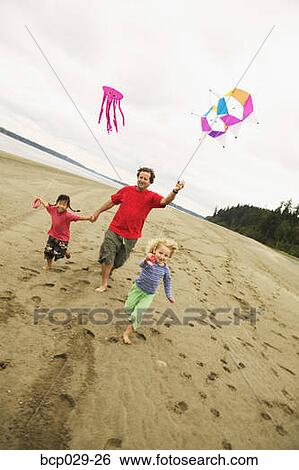 Father and children flying kites on a beach View Large Photo Image Stock Photograph - Father and children flying kites on a beach. Fotosearch